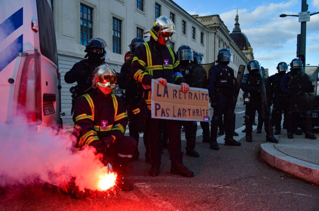 Les pompiers qui protestent pendant la manifestation contre la réforme des retraites se prennent en photo devant les CRS, à la sortie du Pont de Guillotière.