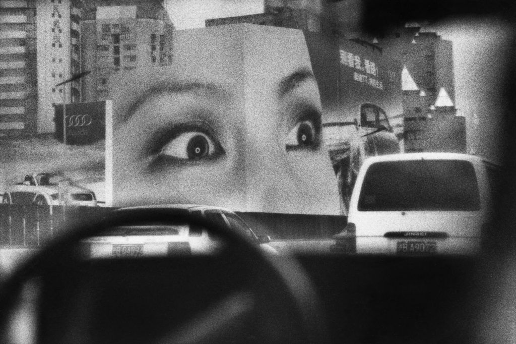 Sans titre. Shangai, Chine. 2002 À Shanghai en 2002, le boom économique bat son plein et des affiches publicitaires géantes animent les rues. Cette photographie est prise à travers le pare-brise d’un taxi. © Marc Riboud / Fonds Marc Riboud au MNAAG